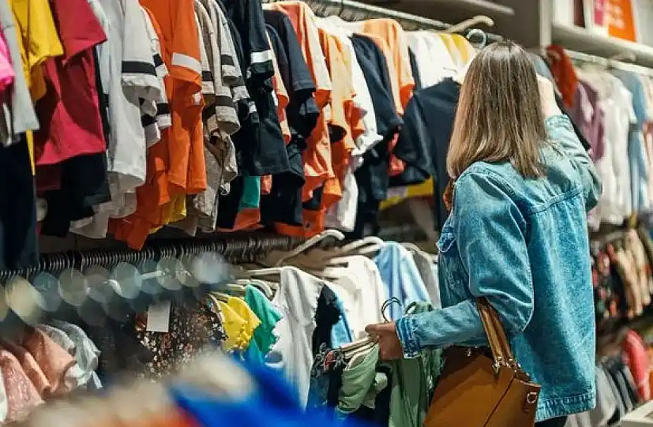 Mujer eligiendo ropa en tienda de ventas PyME